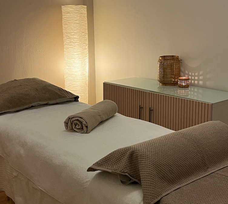 Yoga Kendra Yoga Studio in central Malmö Wellness Treatments A peaceful massage room containing a treatment table neatly made with a white sheet, a brown pillow, and a rolled towel.
