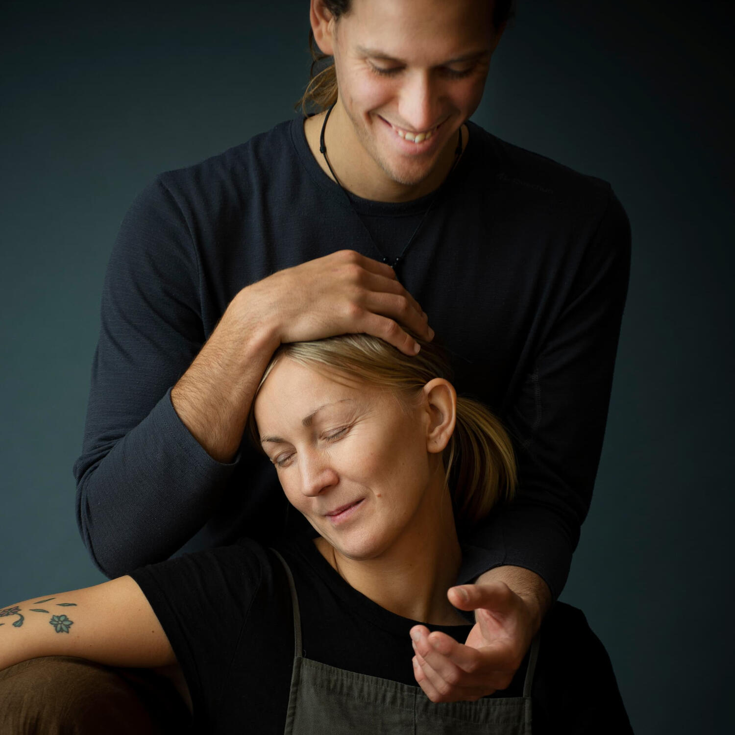 Zenthai Shiatsu Massage Therapy Yoga Kendra Malmö A smiling man gently cradles the head of a blonde woman who has her eyes closed in a calm expression